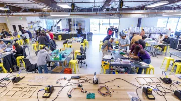 Students building prototypes in makerspace using 3D printers soldering stations and fabrication tools