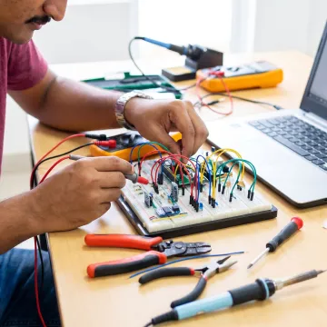 Learner testing an electronics project on a workbench