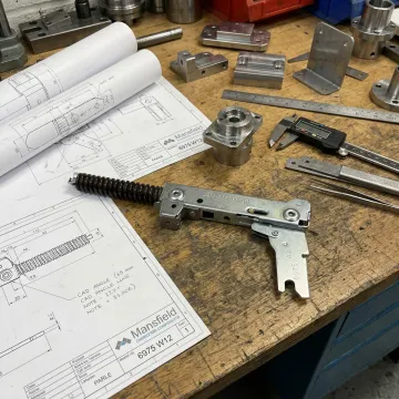 Custom angle hinge brackets and fittings on an engineering bench