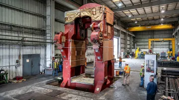Large industrial aluminum forging press producing structural aerospace components in manufacturing facility