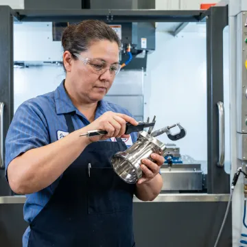 Technician inspecting machined aerospace part