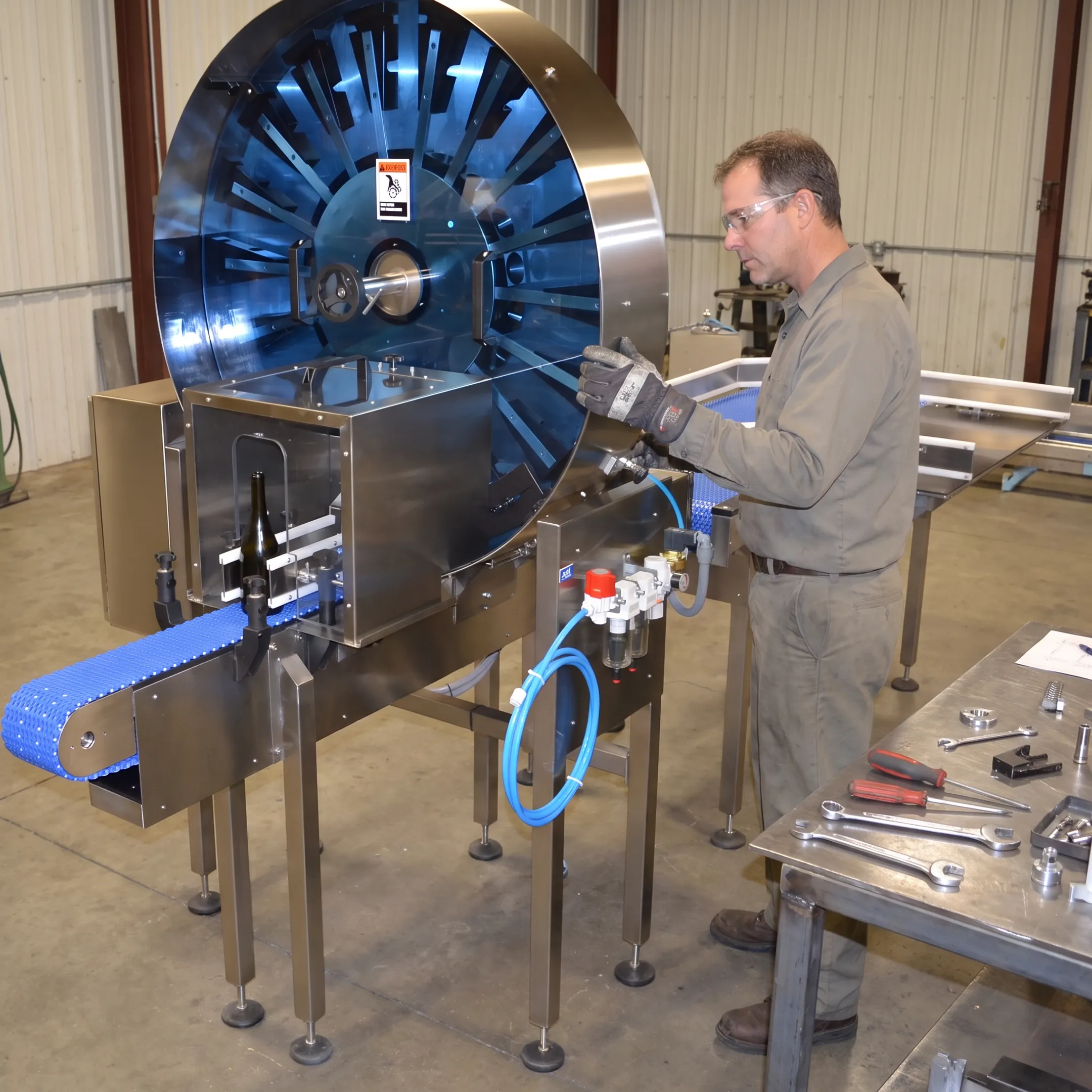 Custom fabricated container-cleaning machinery being inspected by an engineer
