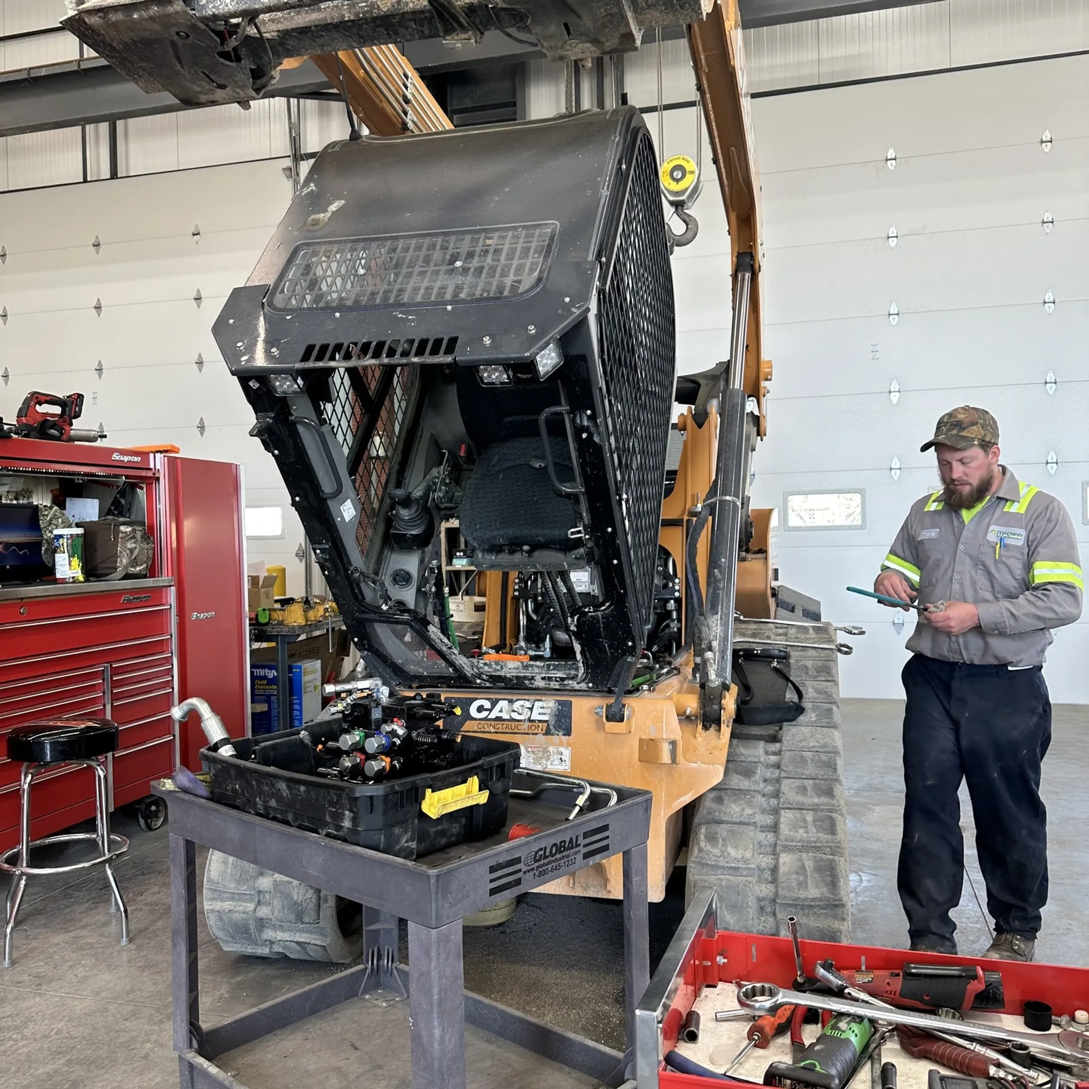 Technician repairing a hydraulic cylinder and inspecting construction equipment components
