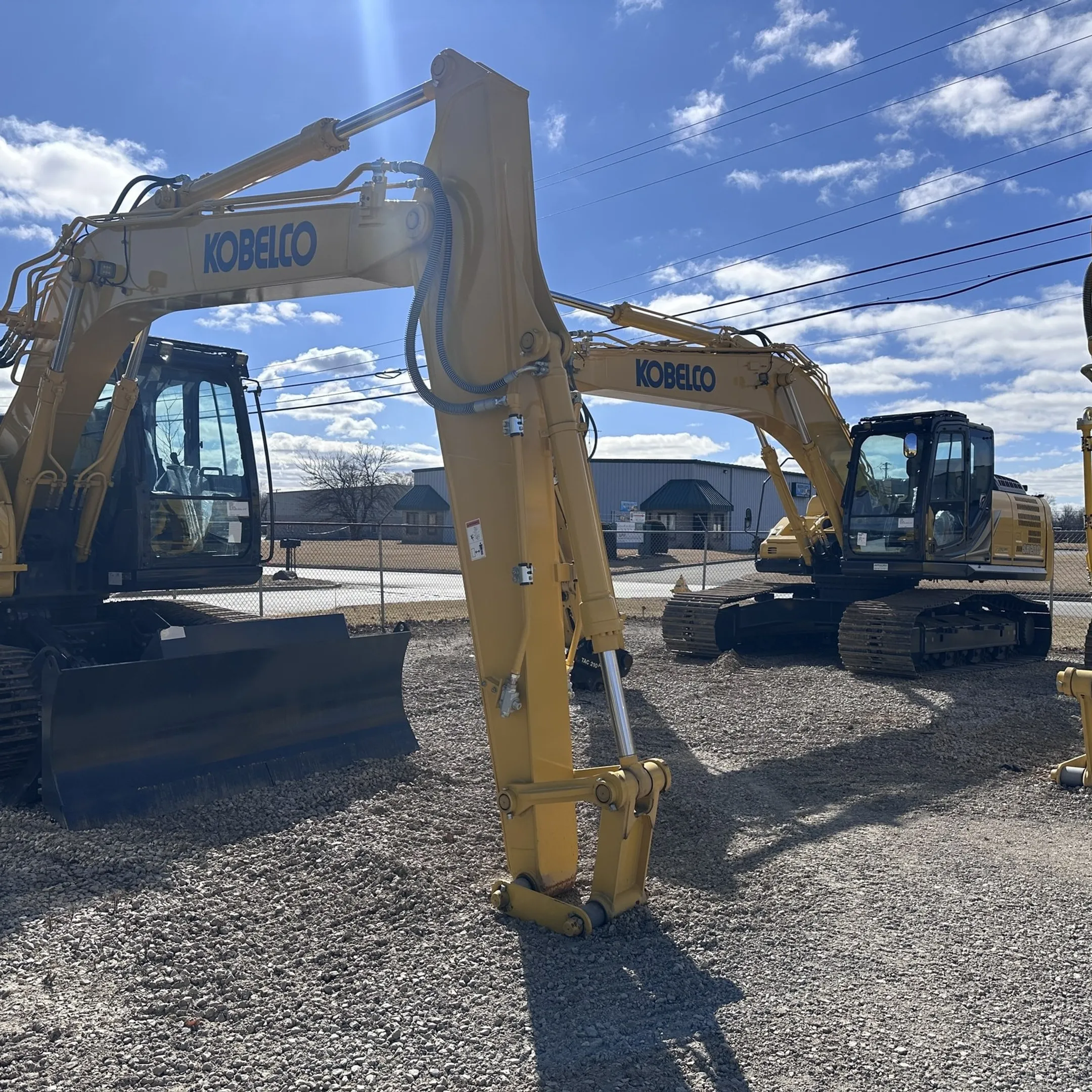 Manager reviewing heavy equipment telematics data on a laptop beside a construction fleet