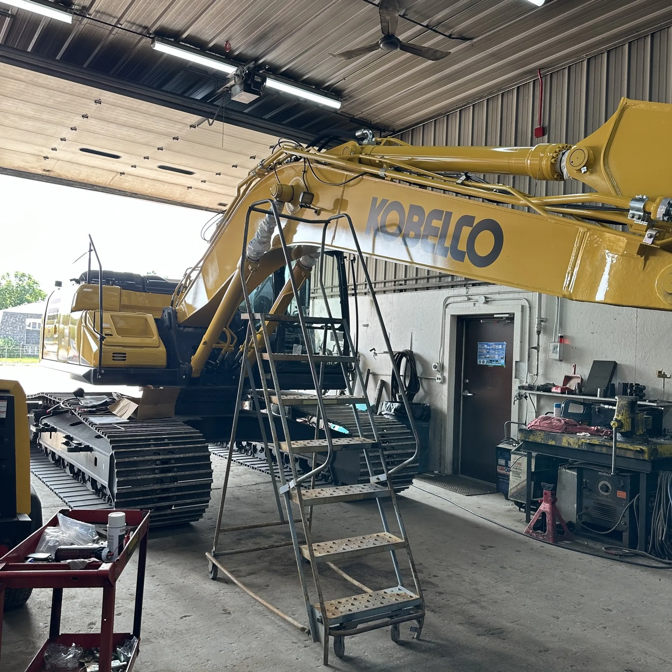 Technician diagnosing hydraulic equipment beside an excavator