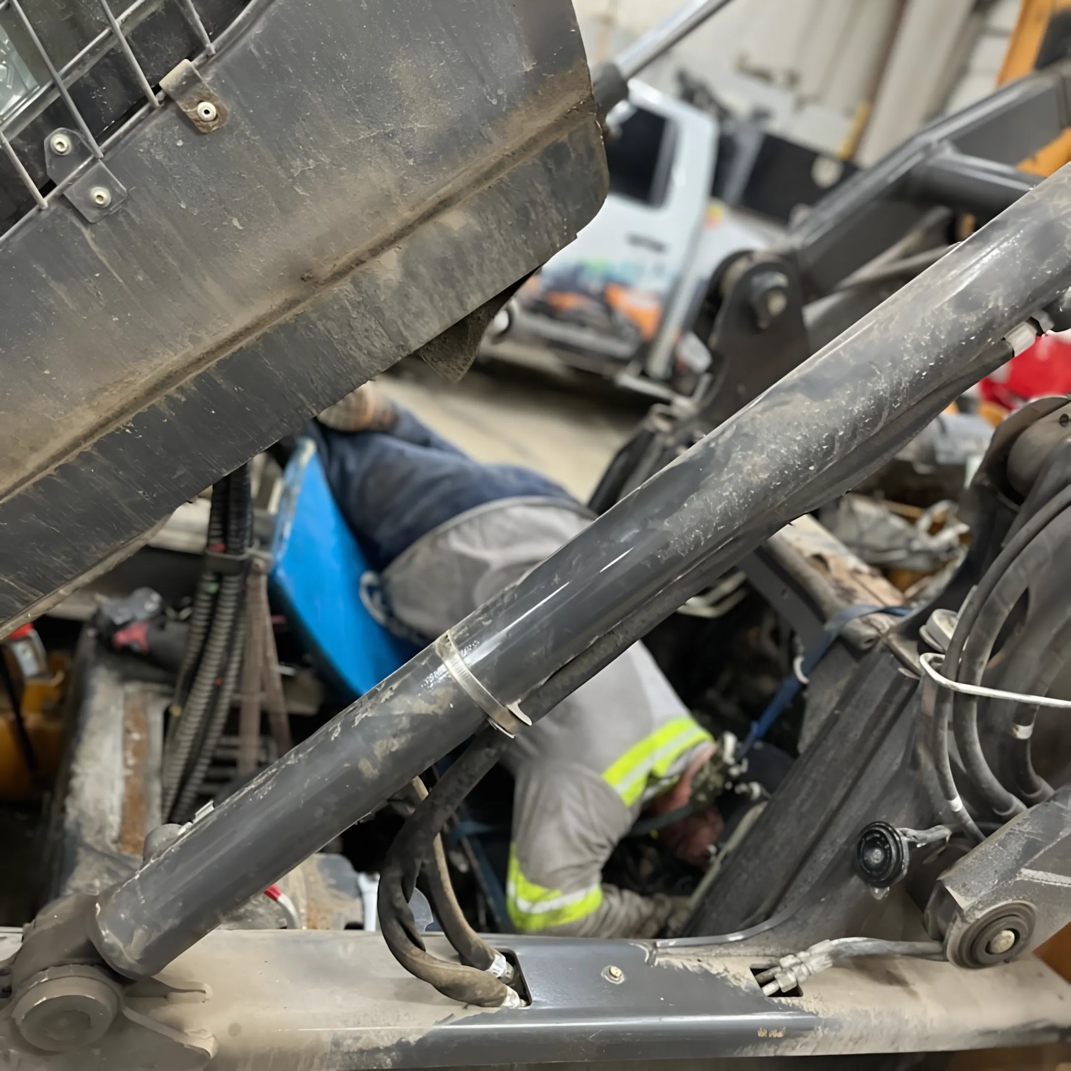 Technician examining hydraulic components on heavy equipment