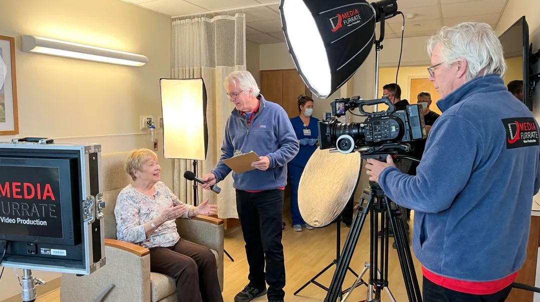 Videographer conducting off-camera patient testimonial interview in clinical setting
