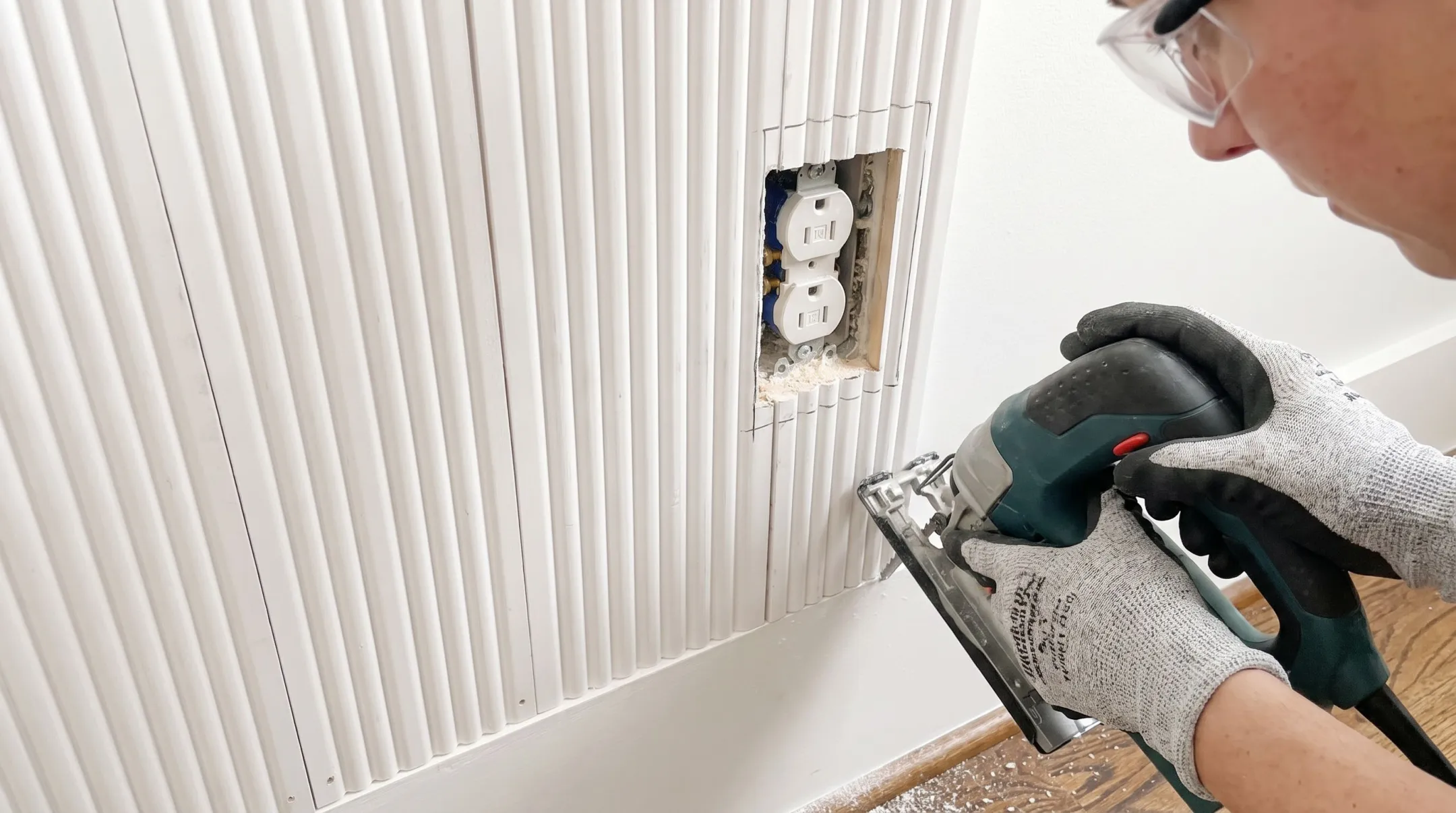 Contractor cutting slatwall panel around electrical outlet with jigsaw