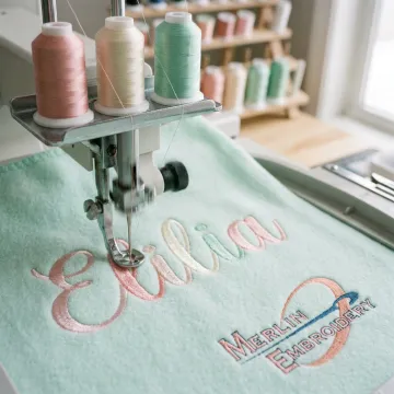 Embroidery machine stitching a baby name on a soft blanket