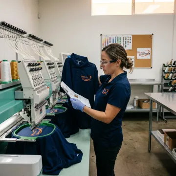 Custom polo shirts being embroidered in bulk