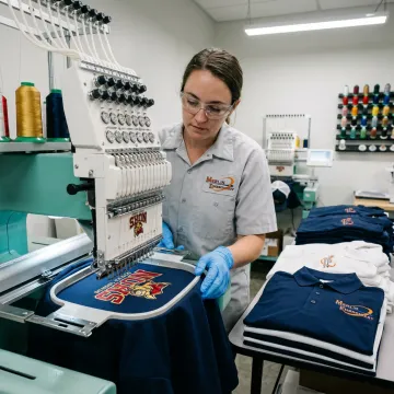 Embroidery machine stitching a school logo on a teacher polo shirt