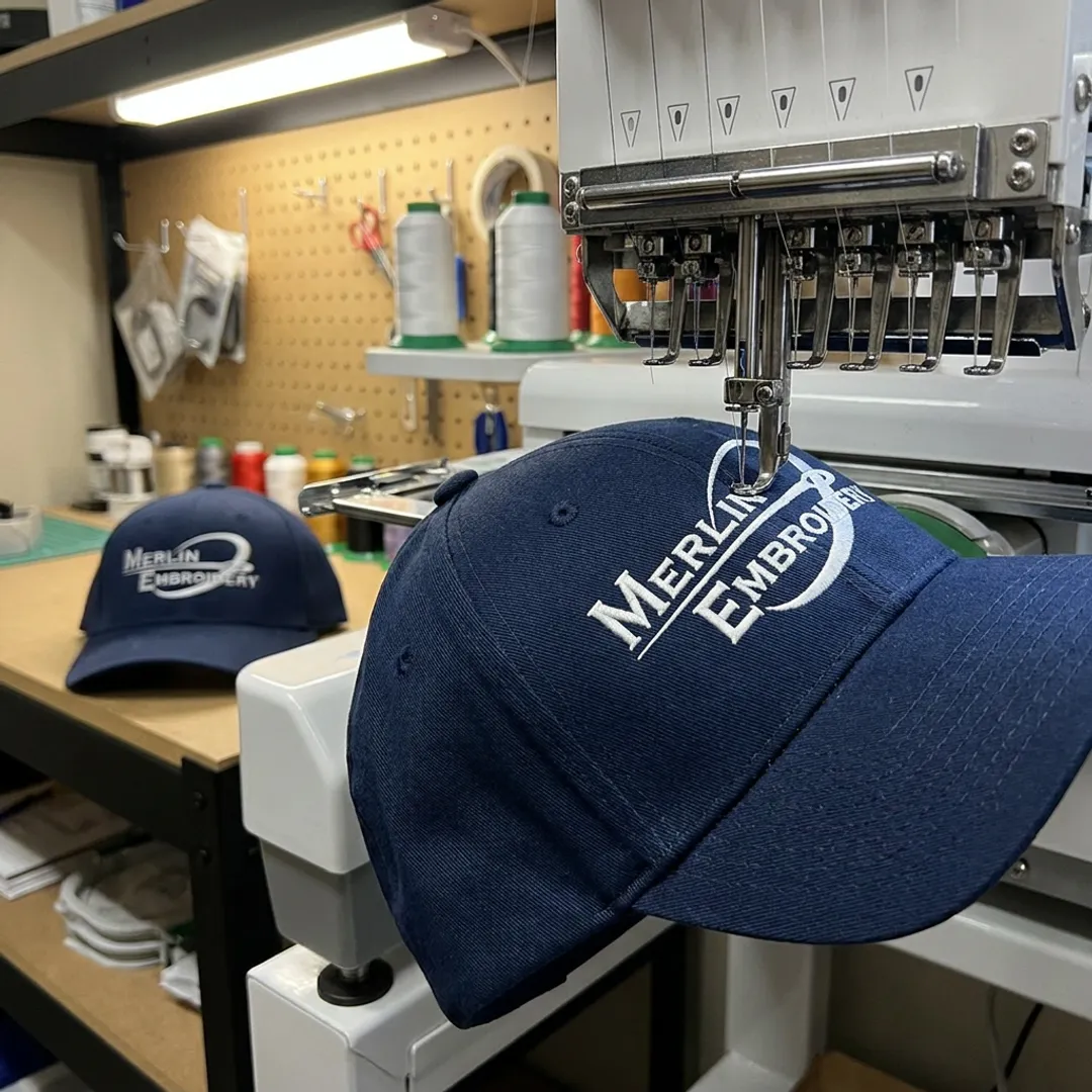 Embroidery machine stitching a navy hat