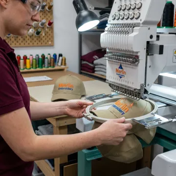 Embroidery machine stitching a logo on a baseball cap