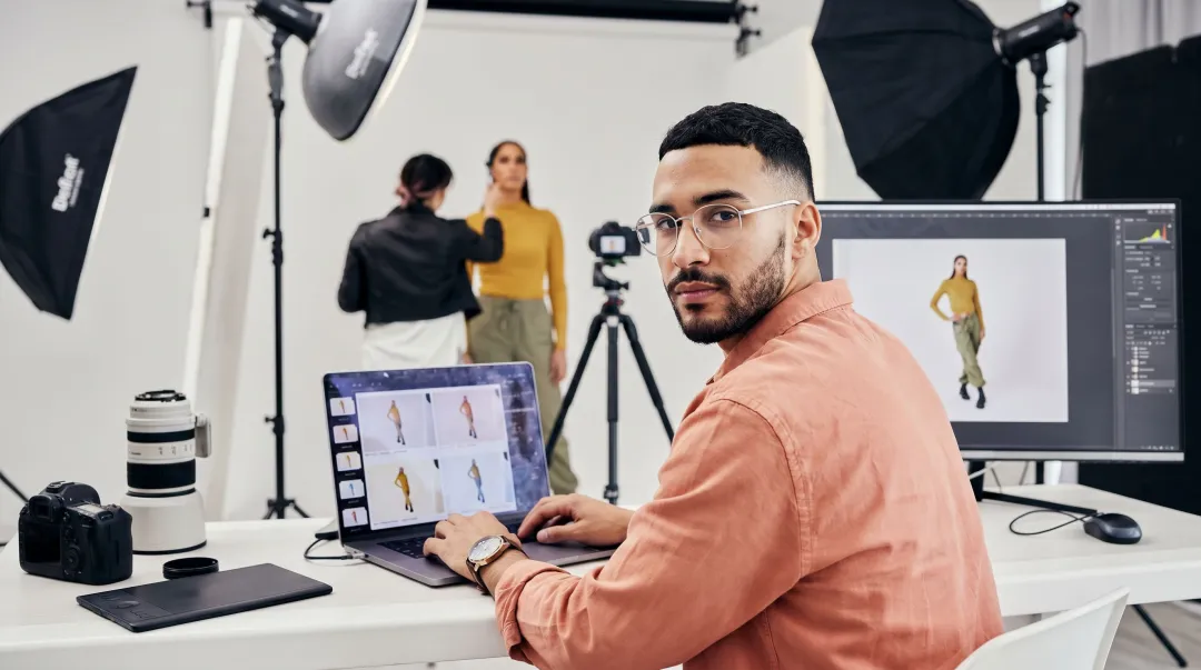 Fashion photographer reviewing work on laptop representing AI industry workforce displacement impact