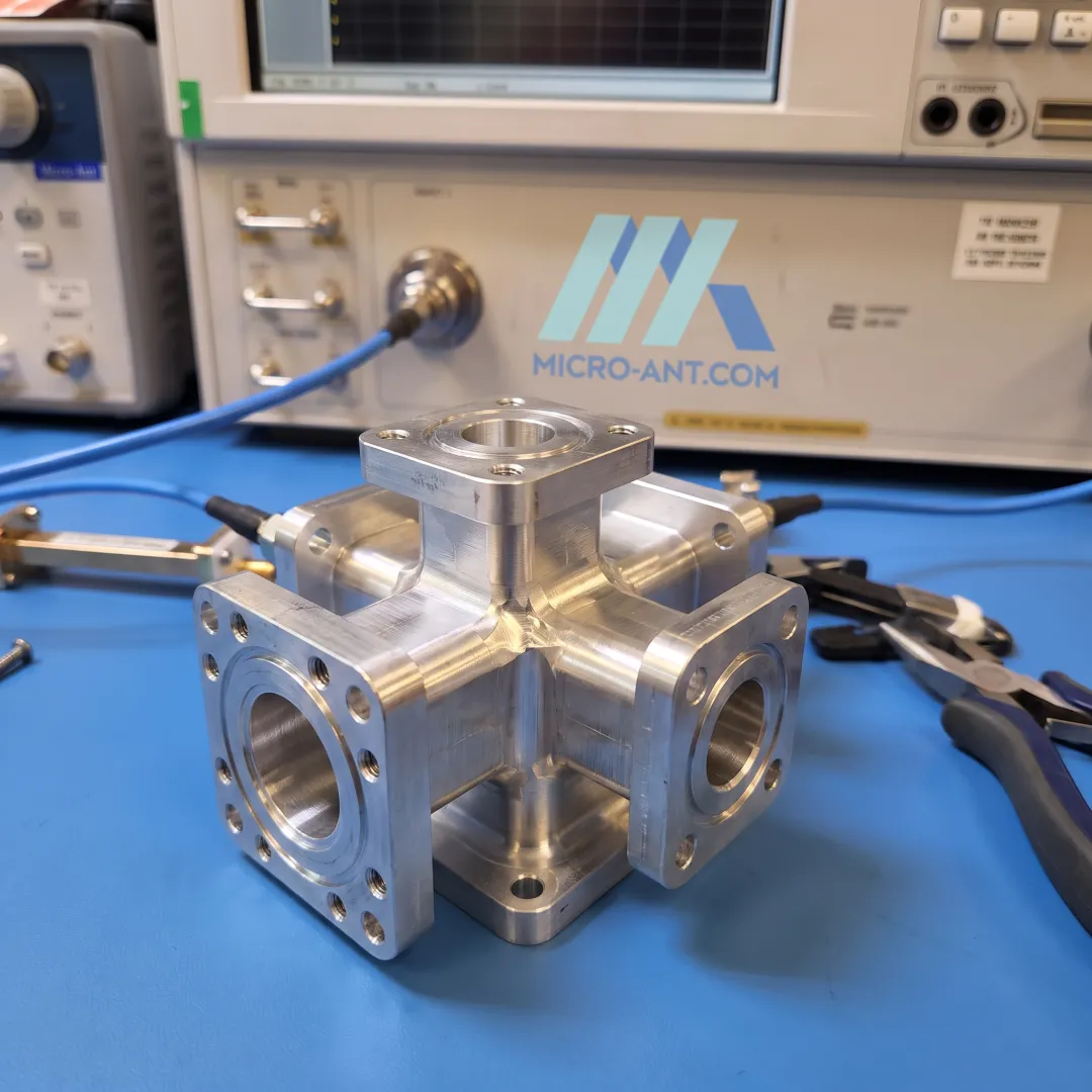 Engineer inspecting an orthomode transducer component in an RF antenna manufacturing facility