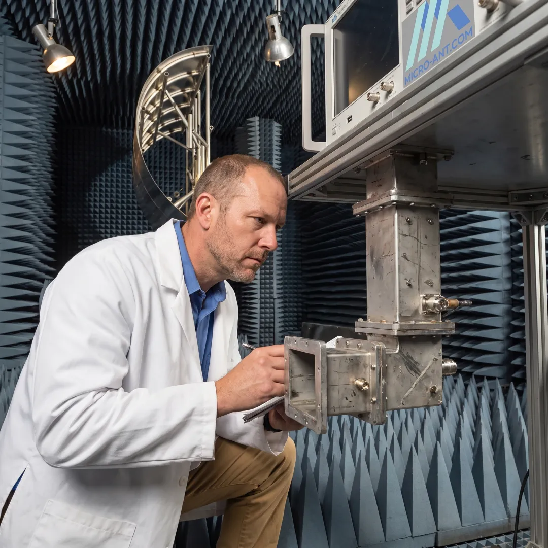 Engineer inspecting a waveguide component during quality testing