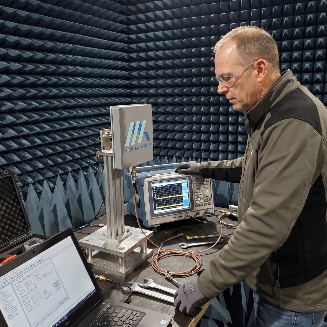 Engineer inspecting a SATCOM antenna in a test facility