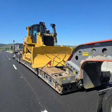 Heavy equipment transport truck carrying bulldozer on highway