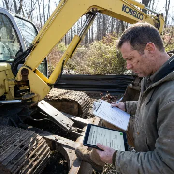 Broker inspecting heavy equipment before auction listing