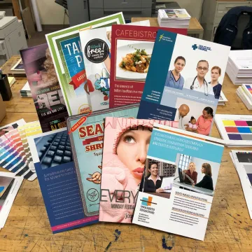 Stacks of colorful flyers and marketing materials at a commercial print shop
