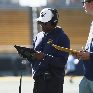 Football coaches reviewing live analytics on a sideline tablet