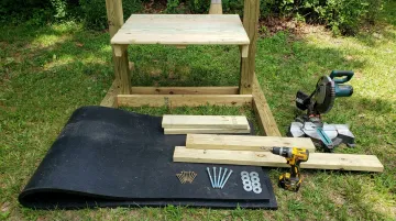 Stack of stall mats treated lumber and tools for building DIY archery backstop