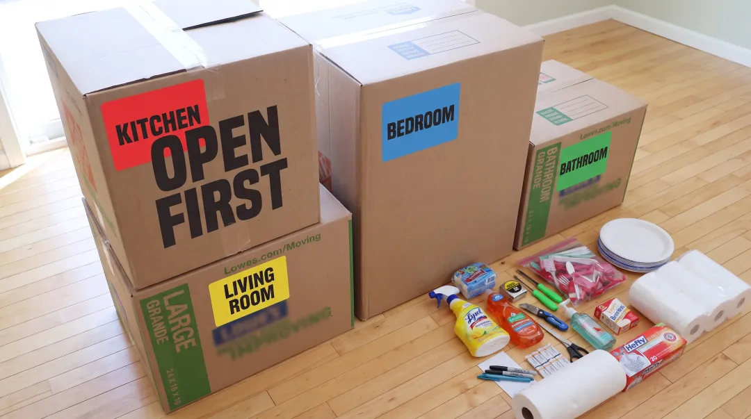 Organized moving boxes labeled by room with color-coded tags and inventory system