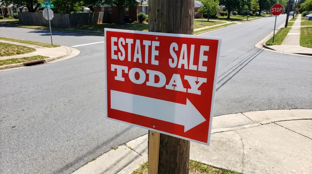 Estate sale directional signage with bold arrows posted at neighborhood intersection