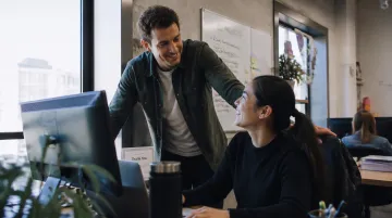 Manager providing specific recognition feedback to employee in modern office setting during one-on-one meeting
