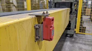 Industrial IP67 rated safety interlock switch mounted on conveyor guard in production environment