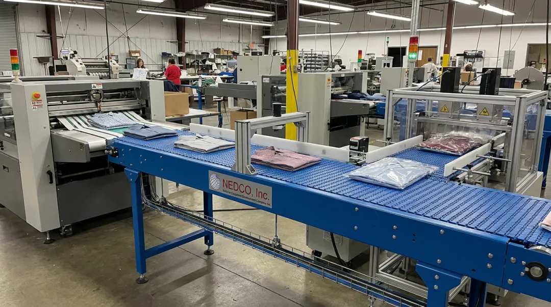 NEDCO CV-500 conveyor system connecting folding and bagging stations