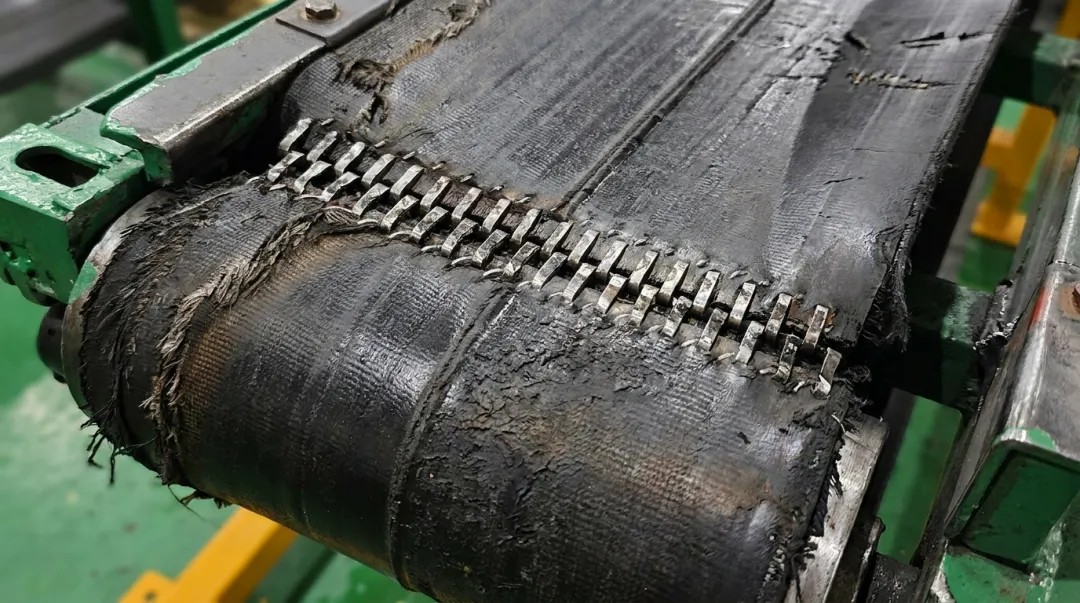 Close-up of conveyor belt splice joint showing angled cut and misalignment defect