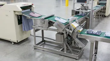 NEDCO E-Z Fold conveyor system integrated with automated garment folding and packaging equipment