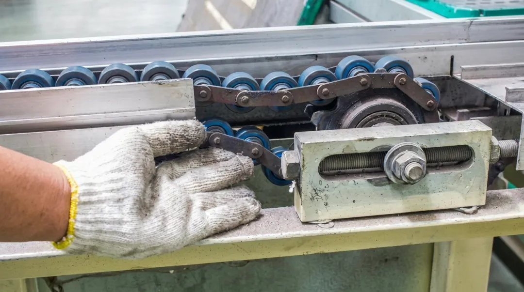 Technician inspecting conveyor belt drive components on industrial garment equipment