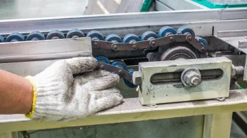Technician inspecting conveyor belt drive components on industrial garment equipment