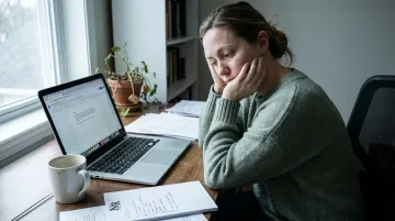 Adult professional sitting alone at desk overwhelmed by unfinished tasks and disorganization