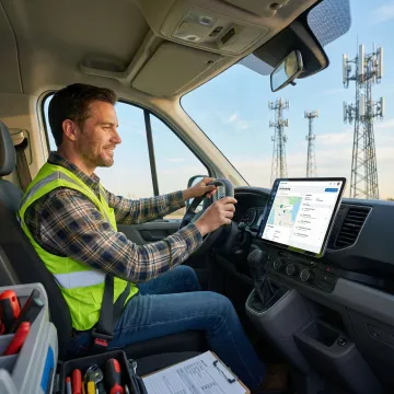 Telecom field technician using field service management software on a tablet beside a utility vehicle
