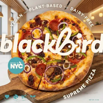 Freshly made vegan pizza with colorful plant-based toppings on a wooden board in Long Beach, CA