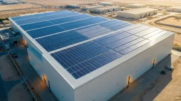Large industrial manufacturing plant with solar panels and wind turbines on facility grounds