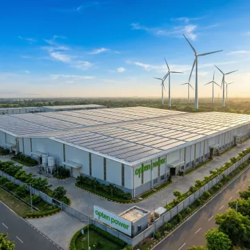 Commercial and industrial facility with solar panels and wind turbines representing clean energy solutions