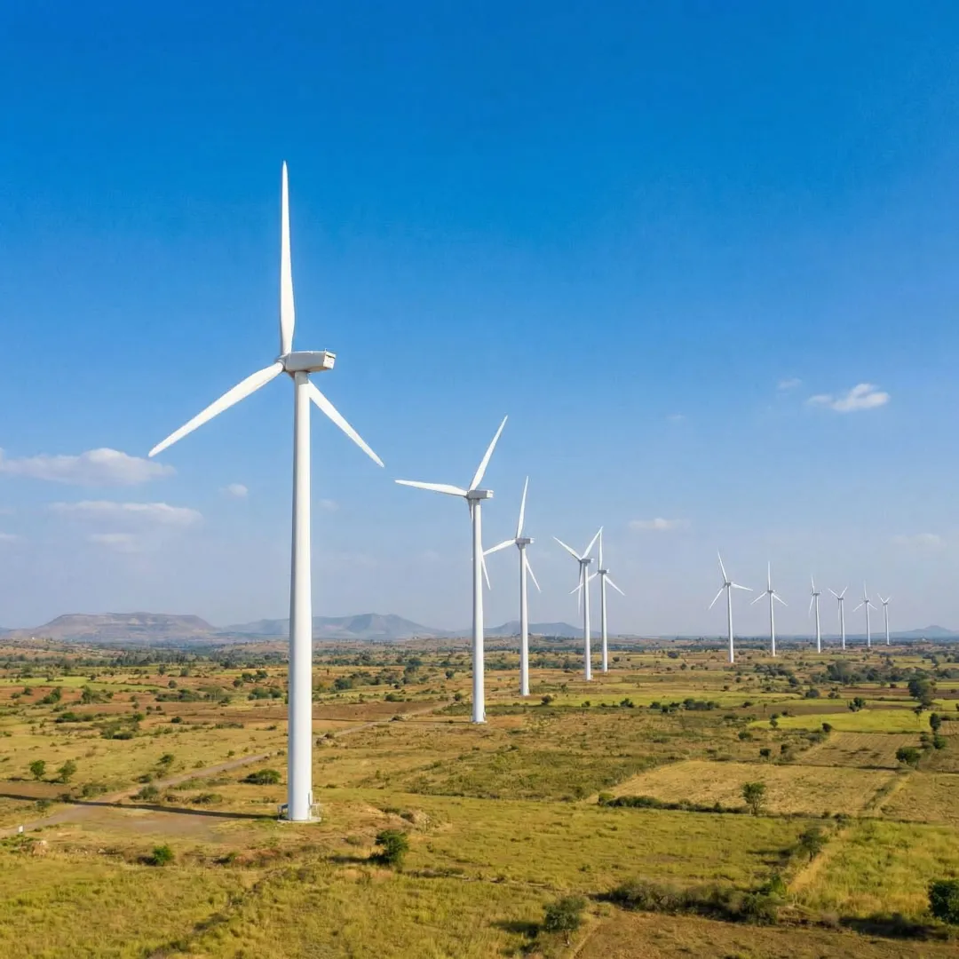 Wind turbines generating clean energy across an Indian landscape under a bright sky