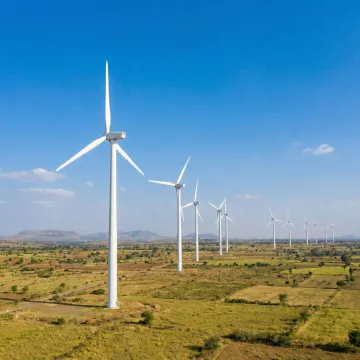 Wind turbines generating clean energy across an Indian landscape under a bright sky