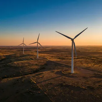 Wind turbines operating across an Indian landscape at sunset