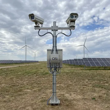Weather sensor station near solar panels and wind turbines