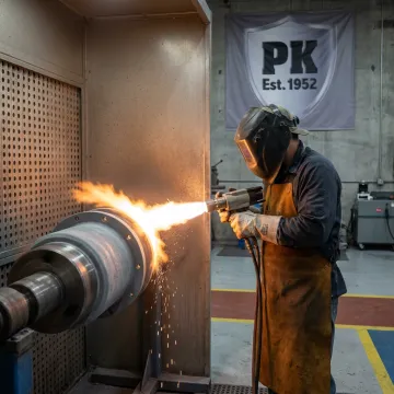 Technician applying industrial coating to metal part