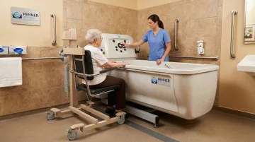 Height-adjustable bathing system with integrated transfer chair in long-term care facility