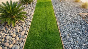 Decorative river rock ground cover in residential yard landscape bed