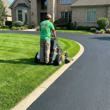 Professional lawn care technician mowing and edging a lush green residential lawn in Buffalo, NY