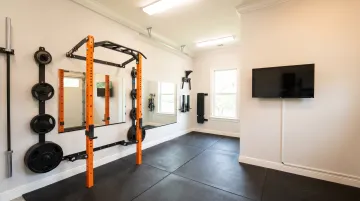 Garage gym setup with power rack rubber flooring and wall mounted TV