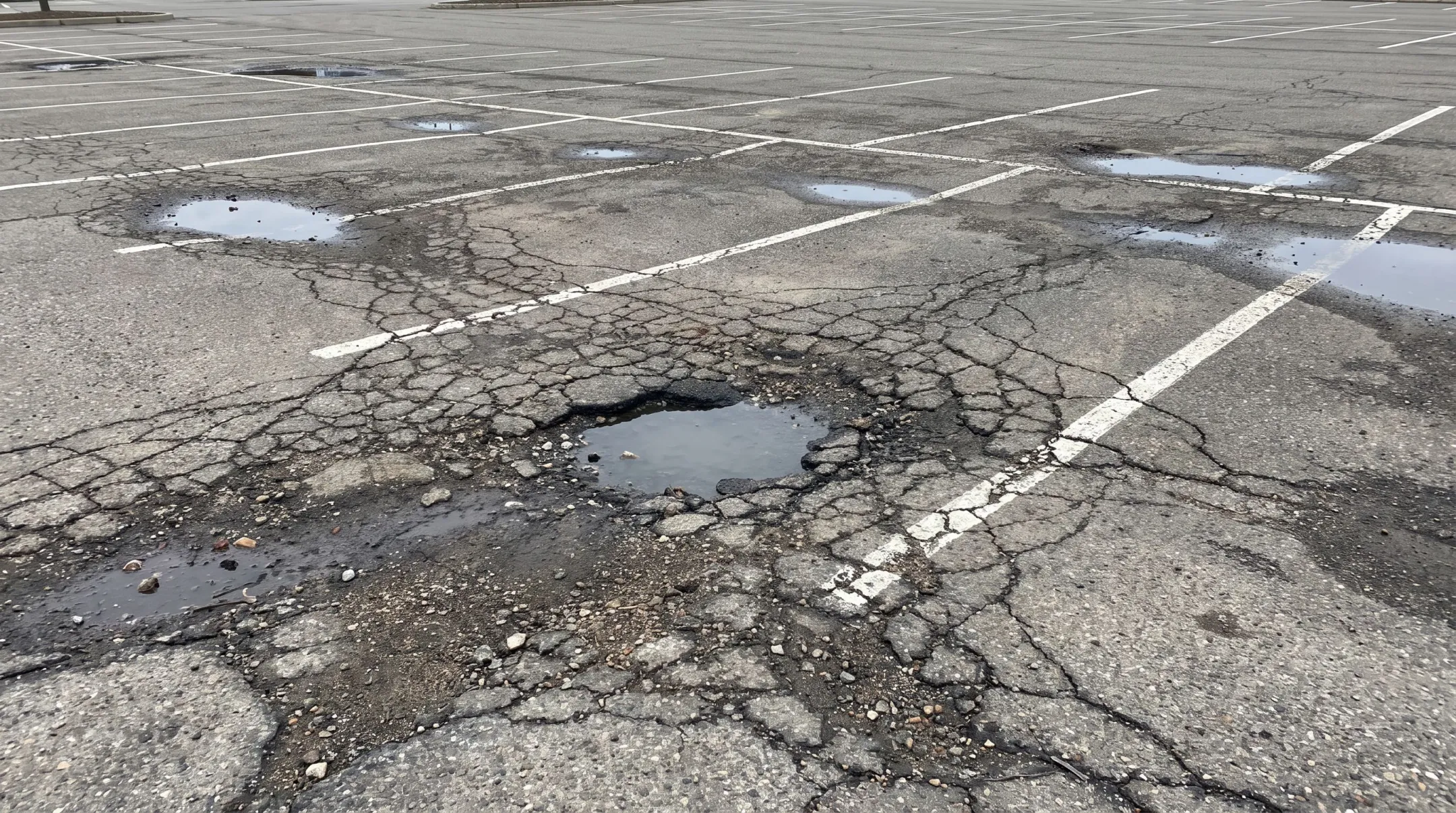 Cracked asphalt parking lot showing potholes and alligator cracking damage